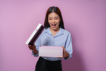 Young woman is surprised and delighted as she opens a gift box, experiencing the joy and excitement of receiving a special present