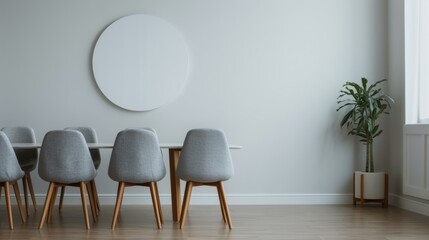 Minimalist office meeting room with a wooden floor, modern chairs, a circular mirror, and a potted plant on a sunny day.