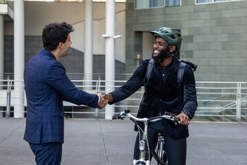 black African businessman on electric bike greets Hispanic colleague in financial district