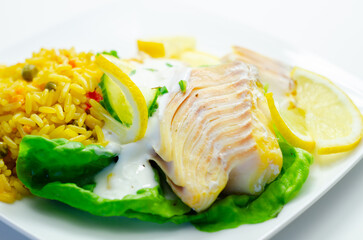 A plate of food with a fish fillet, rice, and lemon slices
