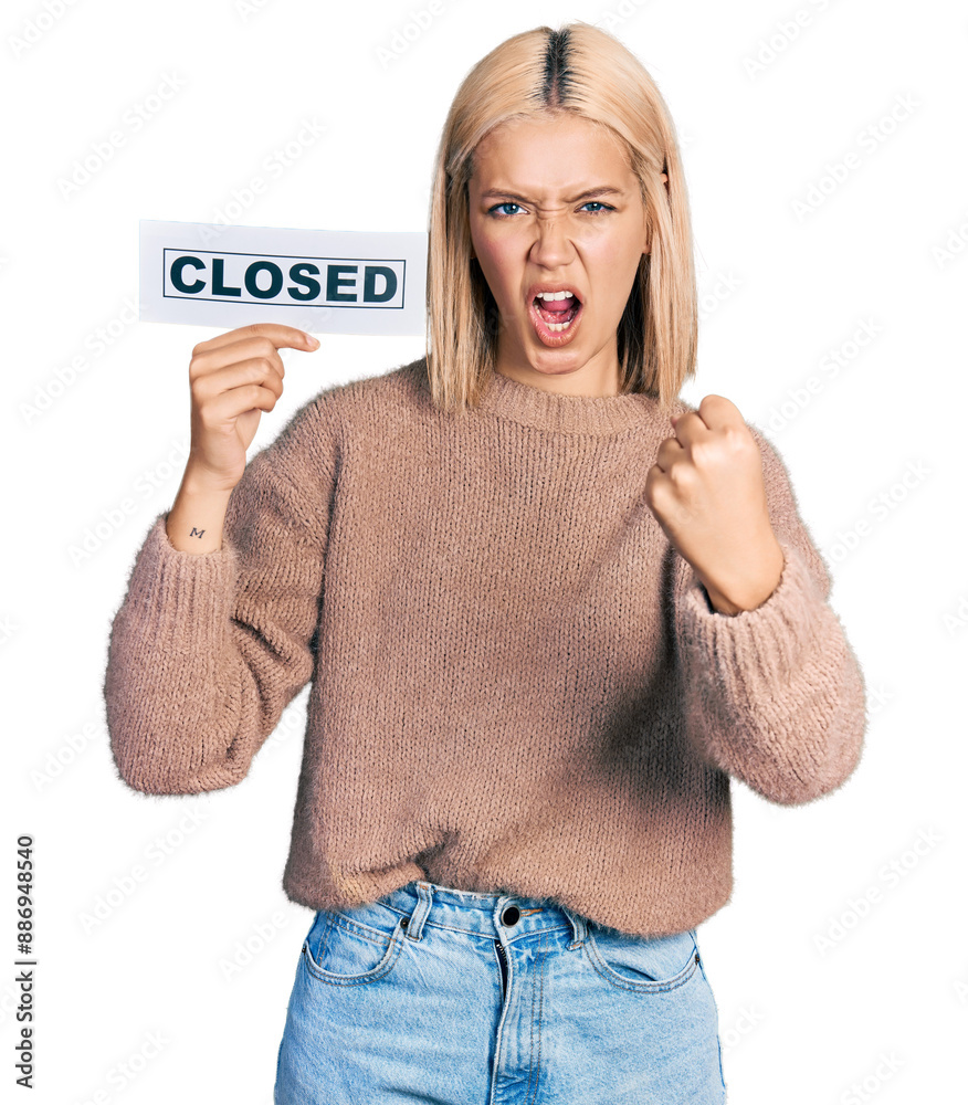 Wall mural beautiful young blonde woman holding closed banner annoyed and frustrated shouting with anger, yelli