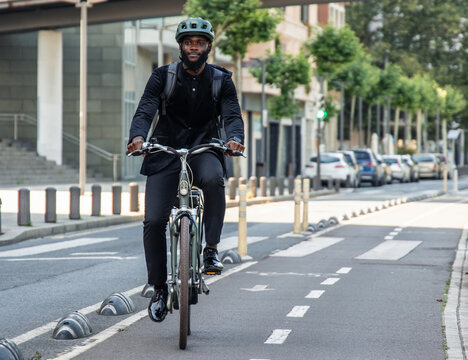 black African businessman on electric bike commuting to work in city bike lane copyspace