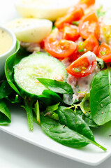 A plate of food with a salad, eggs, and a sauce