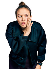 Young hispanic girl wearing sportswear hand on mouth telling secret rumor, whispering malicious talk conversation