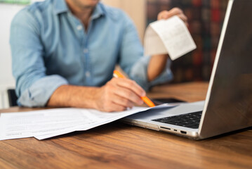 Businessman holds transaction check filling tax forms indicating various sources of income reporting annually in accordance with federal law at workplace with laptop