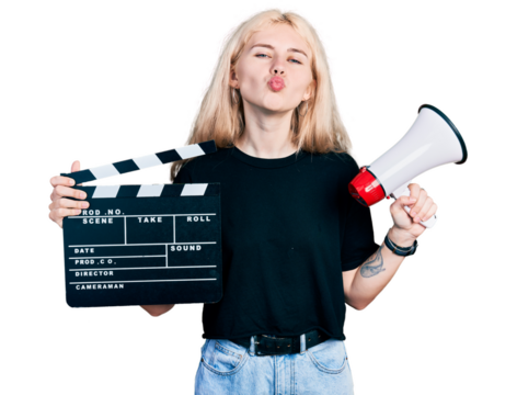 Young caucasian woman holding video film clapboard and megaphone looking at the camera blowing a kiss being lovely and sexy. love expression. - Powered by Adobe