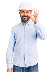 Young handsome man wearing architect hardhat smiling positive doing ok sign with hand and fingers. successful expression.