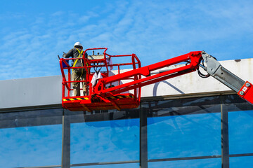 Elevated pedestrian overground tunnel facade painting using a telescopic boom lift with a basket © Zigmunds