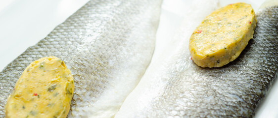 A piece of fish with a herbs butter on top of it