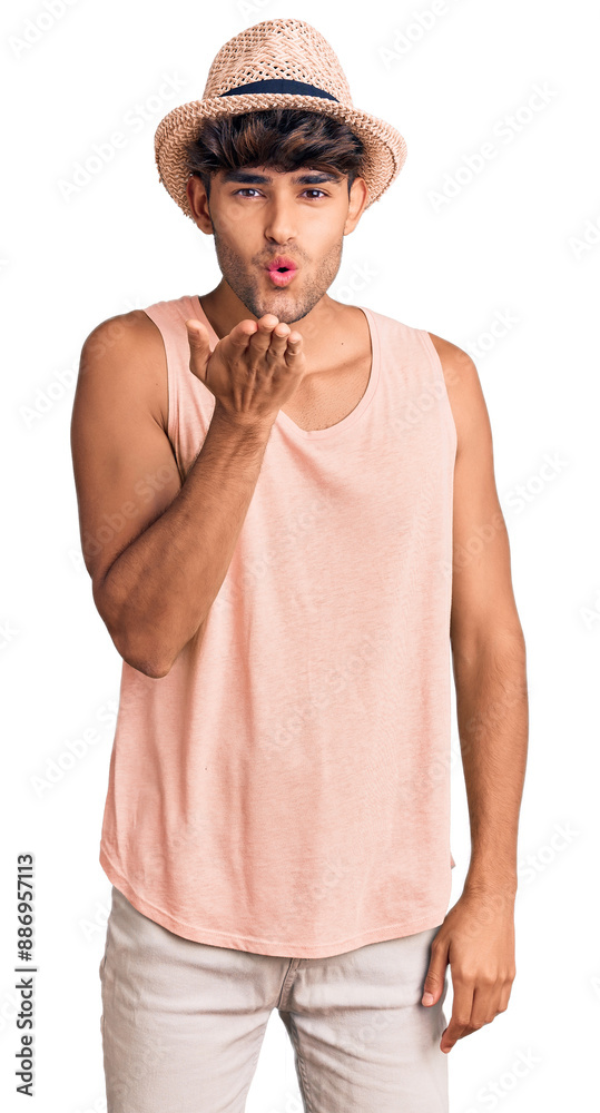 Canvas Prints young hispanic man wearing summer hat looking at the camera blowing a kiss with hand on air being lo