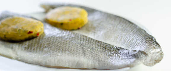 A piece of fish with a herbs butter on top of it