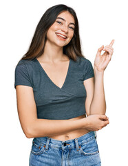 Young beautiful teen girl wearing casual crop top t shirt with a big smile on face, pointing with...