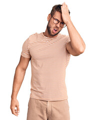 Young caucasian man wearing casual clothes and glasses surprised with hand on head for mistake,...
