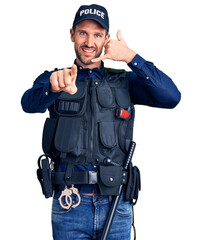 Young handsome man wearing police uniform smiling doing talking on the telephone gesture and pointing to you. call me.