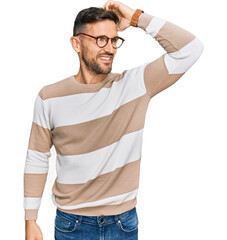 Handsome man with beard wearing casual clothes and glasses smiling confident touching hair with...