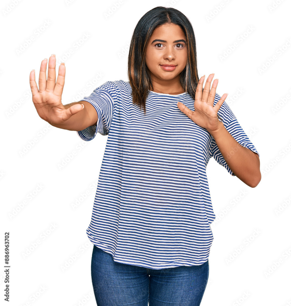 Wall mural Young latin girl wearing casual clothes afraid and terrified with fear expression stop gesture with hands, shouting in shock. panic concept.