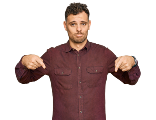 Young hispanic man wearing casual clothes pointing down looking sad and upset, indicating direction with fingers, unhappy and depressed.