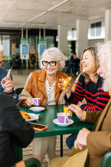 Vertical shot of happy group of senior people laughing and enjoying coffee at cafeteria bar....