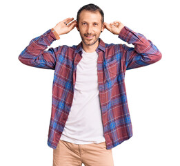 Young handsome man wearing casual clothes smiling pulling ears with fingers, funny gesture....