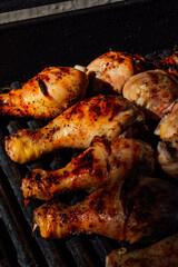 close up of six chicken legs grilling on barbecue in the sun