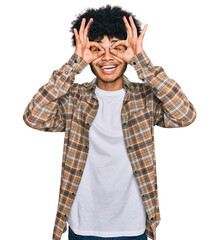 Young african american man with afro hair wearing casual clothes doing ok gesture like binoculars sticking tongue out, eyes looking through fingers. crazy expression.