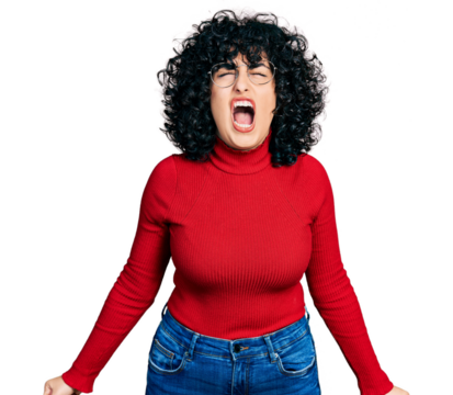 Young middle east girl wearing casual clothes and glasses angry and mad screaming frustrated and furious, shouting with anger. rage and aggressive concept.