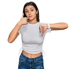 Young hispanic girl wearing casual white t shirt doing thumbs up and down, disagreement and agreement expression. crazy conflict