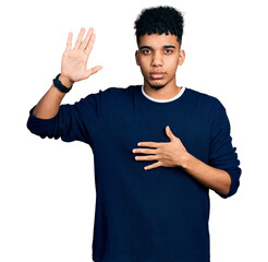 Young african american man wearing casual clothes swearing with hand on chest and open palm, making...
