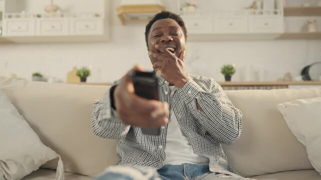Good mood and positive emotions, portrait of laughing black man watching TV. Young adult African American male person enjoying comedy TV show and sitcom, have fun in weekend at home, enjoy solitude