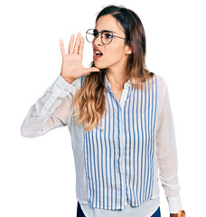 Beautiful hispanic woman wearing casual striped shirt shouting and screaming loud to side with hand on mouth. communication concept.