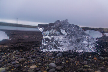 stranded icebergs on a dark pebbly beach in jökulsárlón in iceland