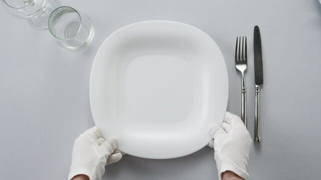 Elegant table setting with white tableware plates, cutlery, and glassware for a classy dining, fancy expensive restaurant dinner