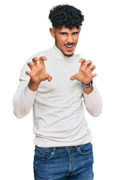 Young arab man wearing casual winter sweater smiling funny doing claw gesture as cat, aggressive and sexy expression
