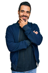 Young hispanic man wearing casual clothes looking confident at the camera smiling with crossed arms and hand raised on chin. thinking positive.