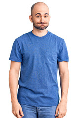 Young handsome man wearing casual t shirt puffing cheeks with funny face. mouth inflated with air, crazy expression.