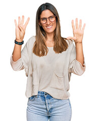 Young woman wearing casual clothes and glasses showing and pointing up with fingers number nine while smiling confident and happy.