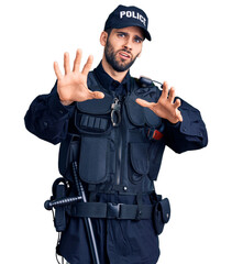 Young handsome man with beard wearing police uniform afraid and terrified with fear expression stop gesture with hands, shouting in shock. panic concept.