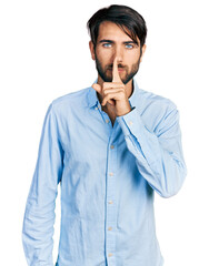 Hispanic man with blue eyes wearing business shirt asking to be quiet with finger on lips. silence and secret concept.