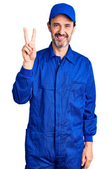 Middle age handsome man wearing mechanic uniform showing and pointing up with fingers number two while smiling confident and happy.