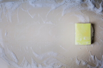 A yellow porous cleaning sponge lies on the floor with a disinfectant. Cleaning concept