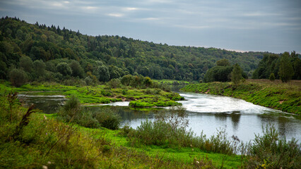 The river landscape is abundant with greenery and a forest, forming a tranquil and peaceful setting