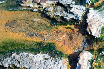 hot water flows from the crack in the colorful rock