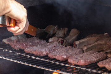 Grilling in action: A chef expertly flips sizzling meats on a smoky barbecue grill, capturing the essence of outdoor cooking and summertime culinary adventures