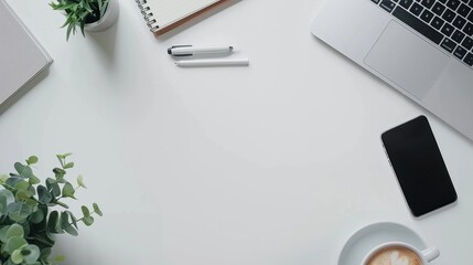 Top view of office essentials including a notepad laptop coffee cup mouse pad and mobile phone with a blank screen Copy space available on the desk workspace