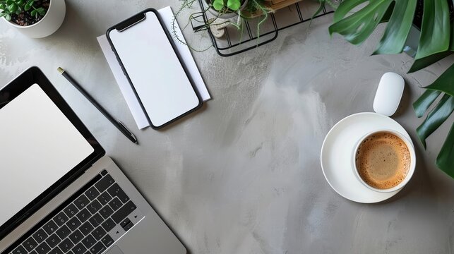 Top view of office essentials including a notepad laptop coffee cup mouse pad and mobile phone with a blank screen Copy space available on the desk workspace