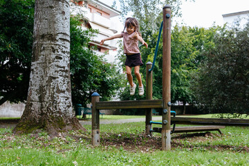 happy little girl jumping from the wooden bench in the park