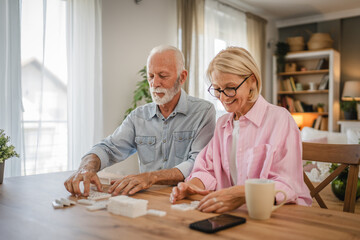 Senior couple husband and wife play dominoes together at home