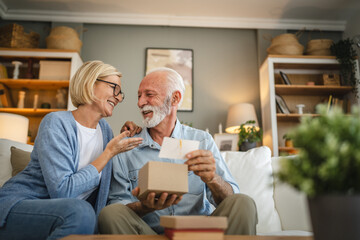 Senior husband read greeting card from a gift with his mature wife