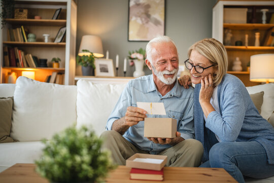 Senior husband read greeting card from a gift with his mature wife