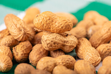 Peanuts, portion of peanuts in shell on a green and white checkered tablecloth. Selective focus.